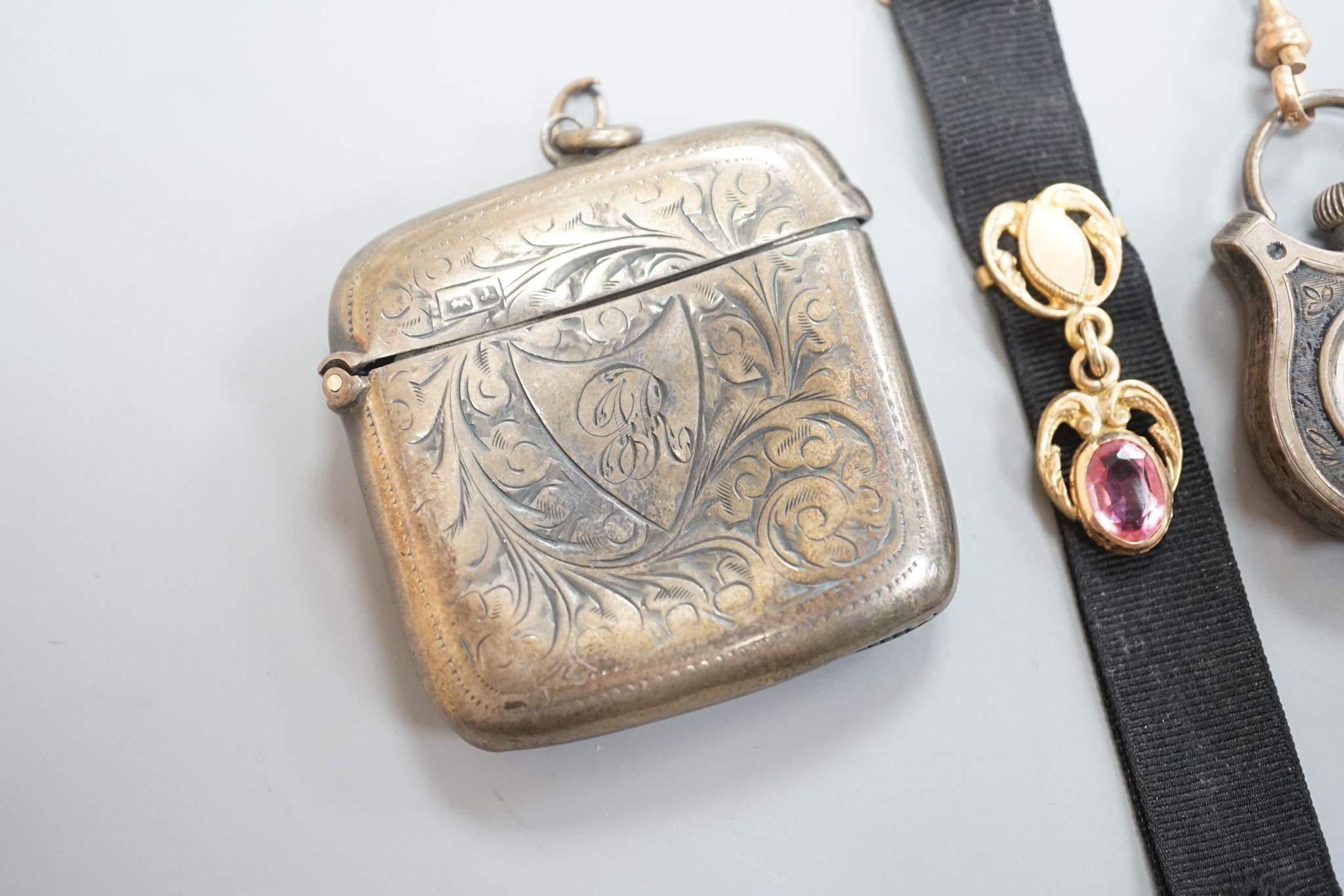 A silver vesta case, 48mm and a white metal cased fob watch, on a black sash suspension.